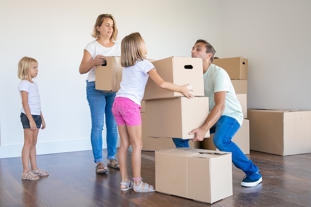 Молодая семья несет коробки в новый дом или квартиру
