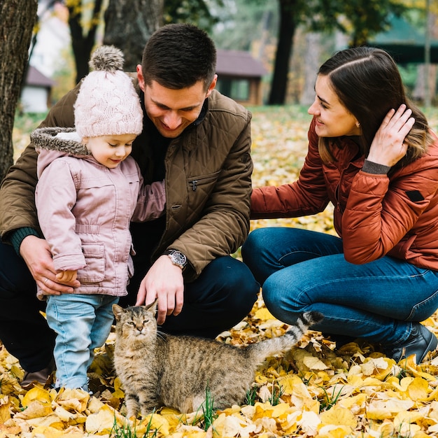 Молодая семья и кошка в парке с осенней листвой