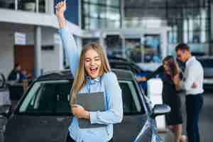 Foto gratuita giovane famiglia che sceglie un'automobile in una sala d'esposizione dell'automobile