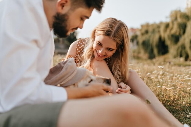 Young family is having fun in park with dog Guy and girl sincerely smiling and looking at their Labrador