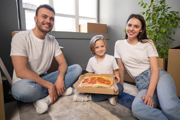 새 집으로 이사하고 피자를 먹는 젊은 가족