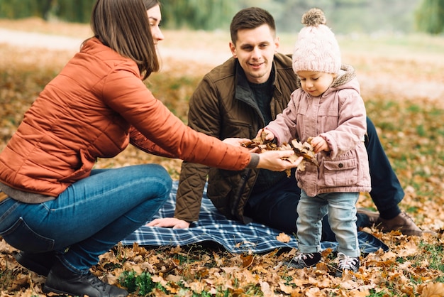 Free photo young family playing with leaves in autumn forest