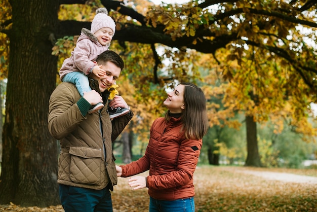 秋の公園で遊歩道をしている若い家族