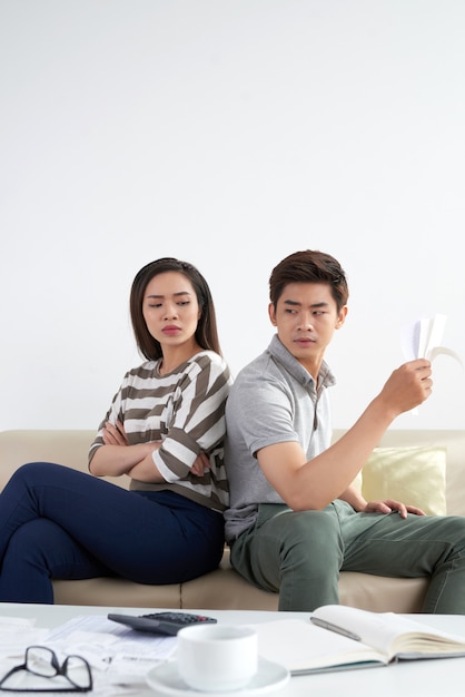 Young family sitting back to back facing financial problems