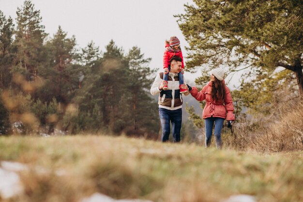 Young family together walking in forest at winter time