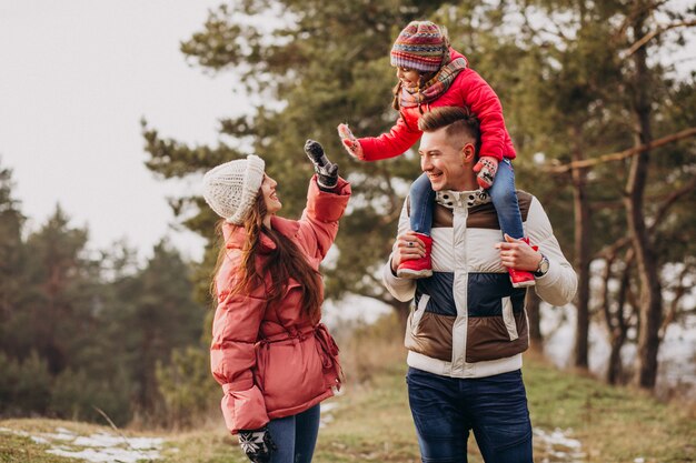 Young family together walking in forest at winter time