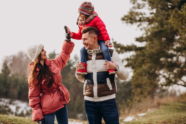 Giovane famiglia che cammina insieme nella foresta all'orario invernale