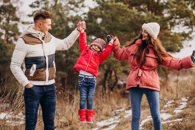 Young family together walking in forest at winter time