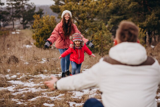 Young family together walking in forest at winter time