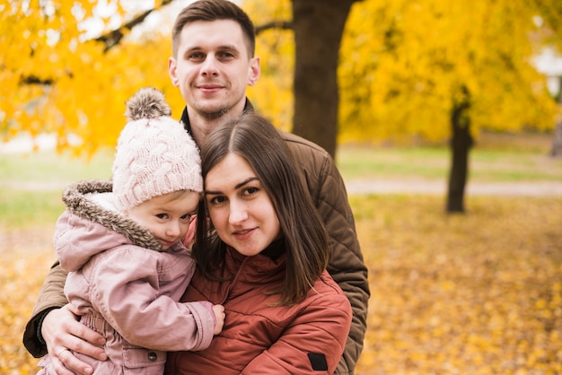 Young family with daughter in park with yellow leaves