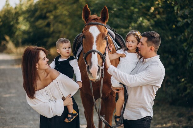 Young family with kids having fun with horse in forest