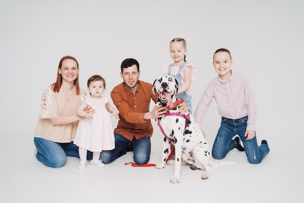 Young Family with kids playing with a dalmatian dog on white background