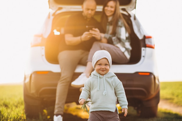 車で旅行する子供たちと若い家族がフィールドに立ち寄った