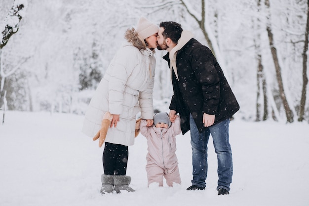 Young family with little daughter in a winter forest full of snow
