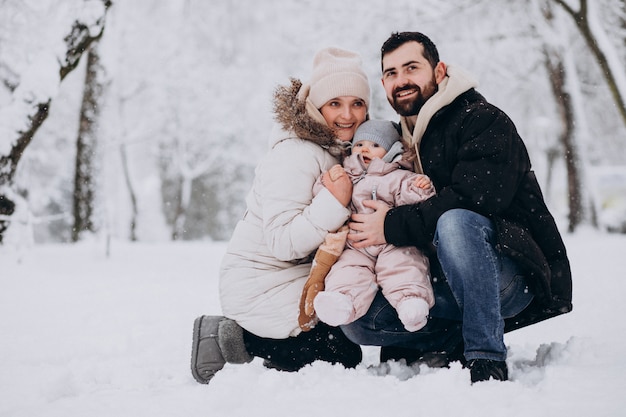 Young family with little daughter in a winter forest full of snow