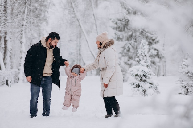 Молодая семья с маленькой дочерью в зимнем лесу, полном снега