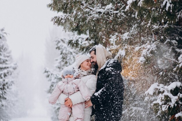 눈이 가득한 겨울 숲에서 작은 딸과 함께 젊은 가족