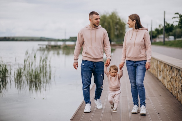 Giovane famiglia con il loro piccolo bambino nel parco in riva al lago