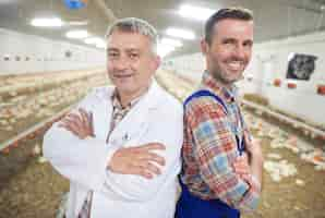 Foto gratuita giovane agricoltore con medico che controlla la salute degli animali