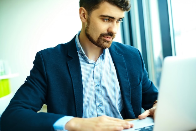 Young fashion handsome smiling hipster man  in the city cafe during lunch time with notebook in suit