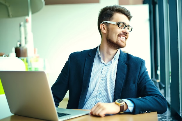 Young fashion smiling hipster man  in the city cafe during lunch time with notebook in suit