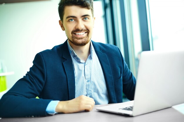 Young fashion smiling hipster man  in the city cafe during lunch time with notebook in suit