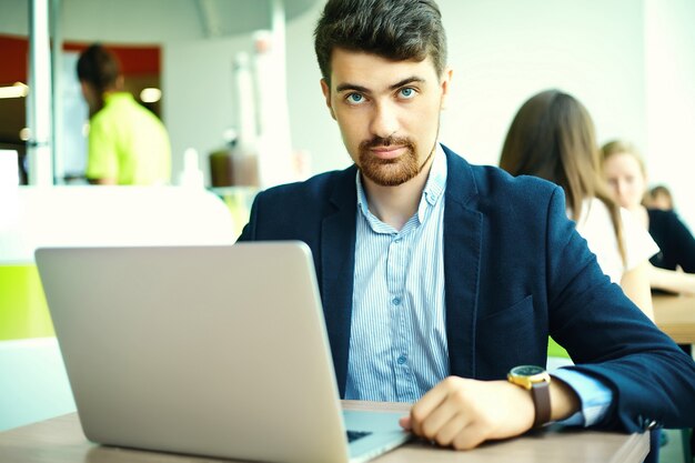 Young fashion smiling hipster man  in the city cafe during lunch time with notebook in suit