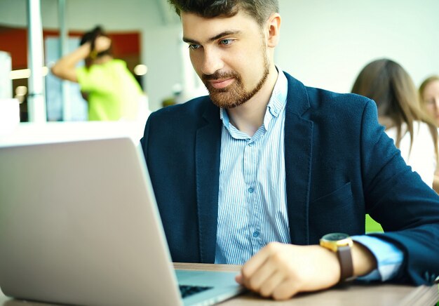 Young fashion smiling hipster man  in the city cafe during lunch time with notebook in suit