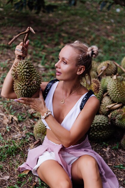 Young fashion woman on a tropical field with durian fruits