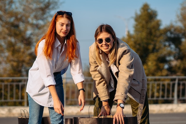 Young fashion women with shopping bags on parking