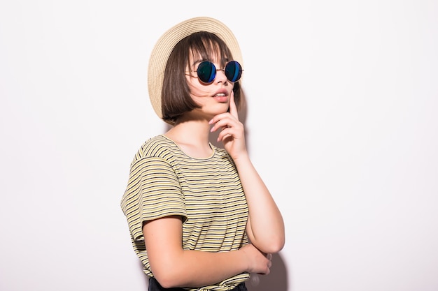 Young fashionable attractive hipster teen girl in sunglasses and straw hat isolated .