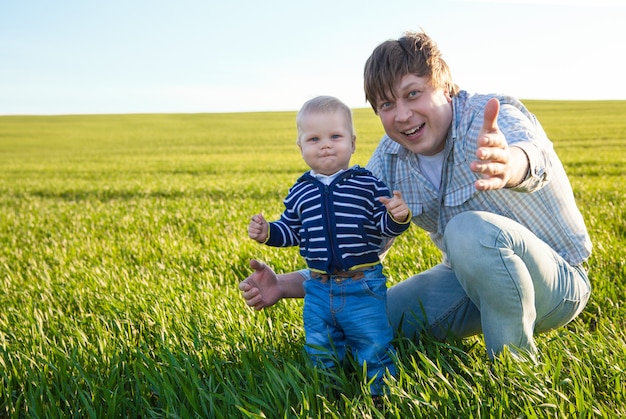 緑​の​野原​で​遊んで​楽しんでいる​若い​父​と​彼​の​息子