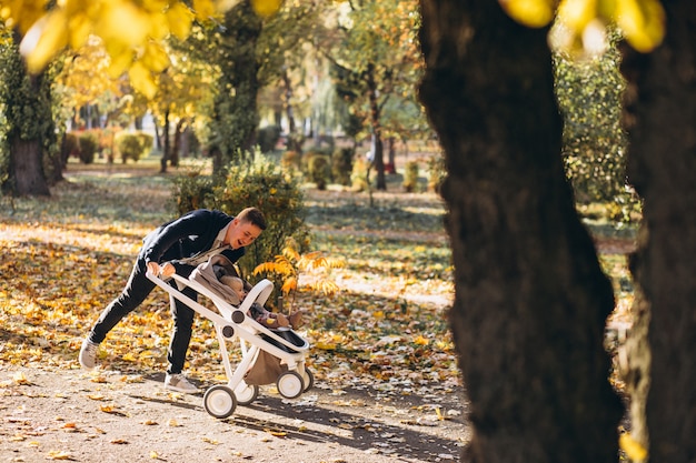 Young father walking with baby daughter in carriage in park