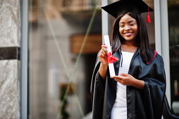 Young female african american student with diploma poses outdoorsxA