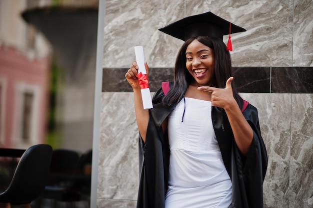 Young female african american student with diploma poses outdoorsxA