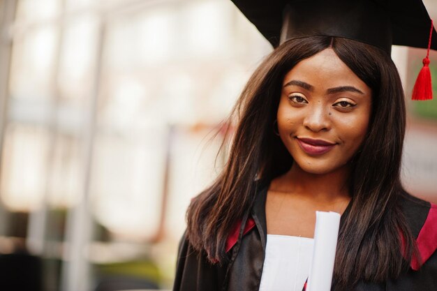 Young female african american student with diploma poses outdoorsxA