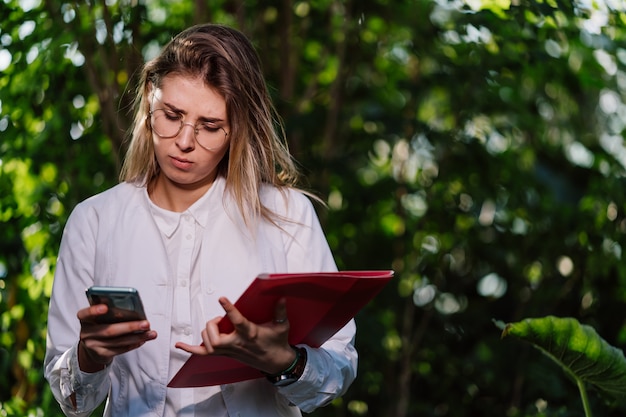 Young female agricultural engineer makes a call in greenhouse