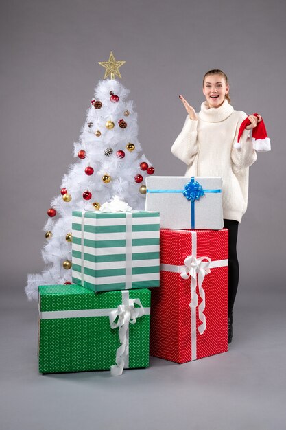 young female around christmas presents on grey