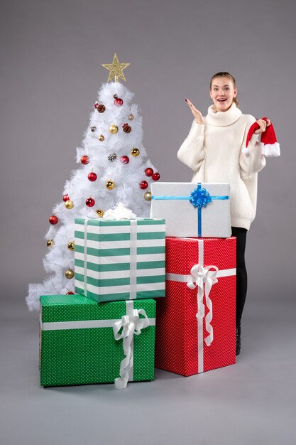 молодая женщина вокруг рождественских подарков на сером
