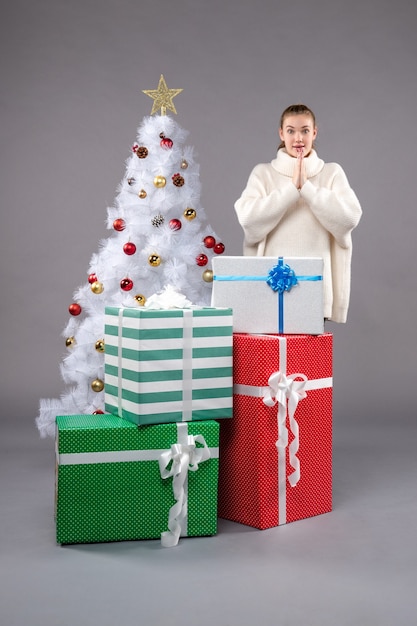 young female around christmas presents on grey