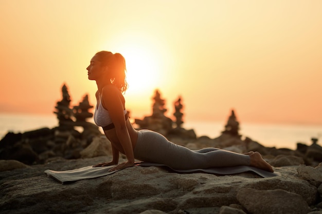 Free Photo  Young woman doing sport exercises on sunrise beach in