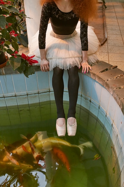 Giovane ballerina femminile che riposa vicino alla piscina in un giardino botanico al chiuso