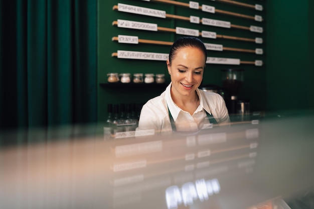 Young female barista standing inside the coffee counter