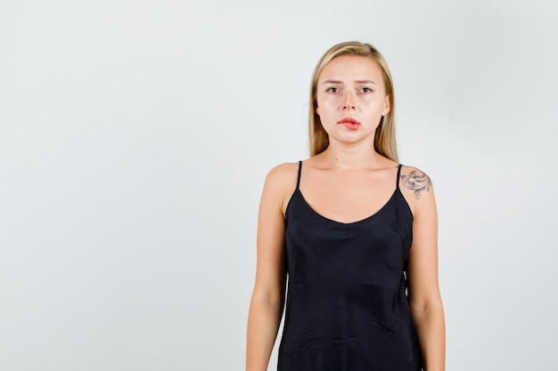 Free photo young female biting lips in black sundress and looking serious.