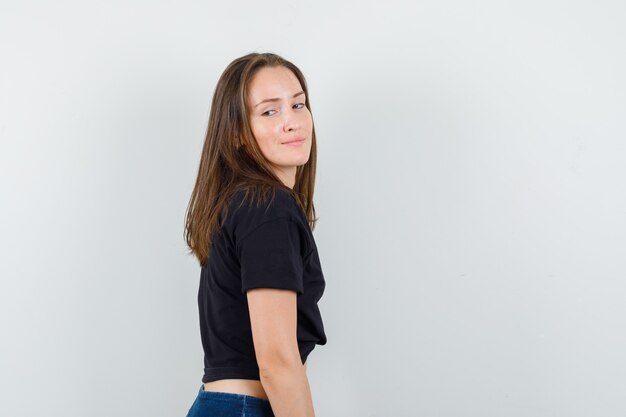 Young female in black blouse, pants looking over shoulder and looking confident