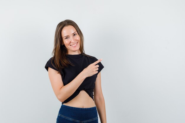 Young female in black blouse, pants pointing away and looking cheerful