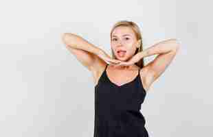 Free photo young female in black singlet holding hands together under chin and looking merry