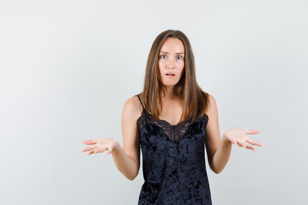 Young female in black singlet showing helpless gesture and looking puzzled