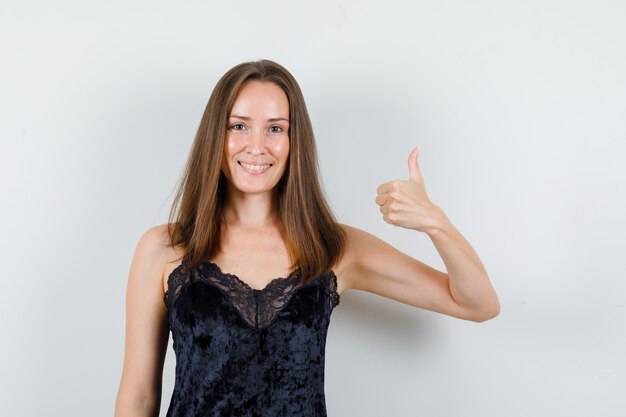 Young female in black singlet showing thumb up and looking cheerful