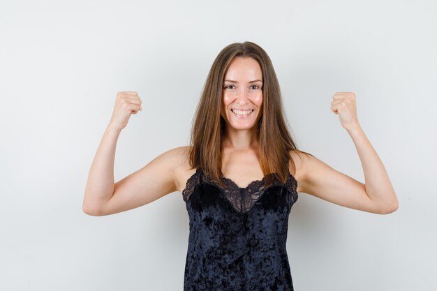 Foto gratuita giovane donna in canottiera nera che mostra il gesto del vincitore e che sembra felice